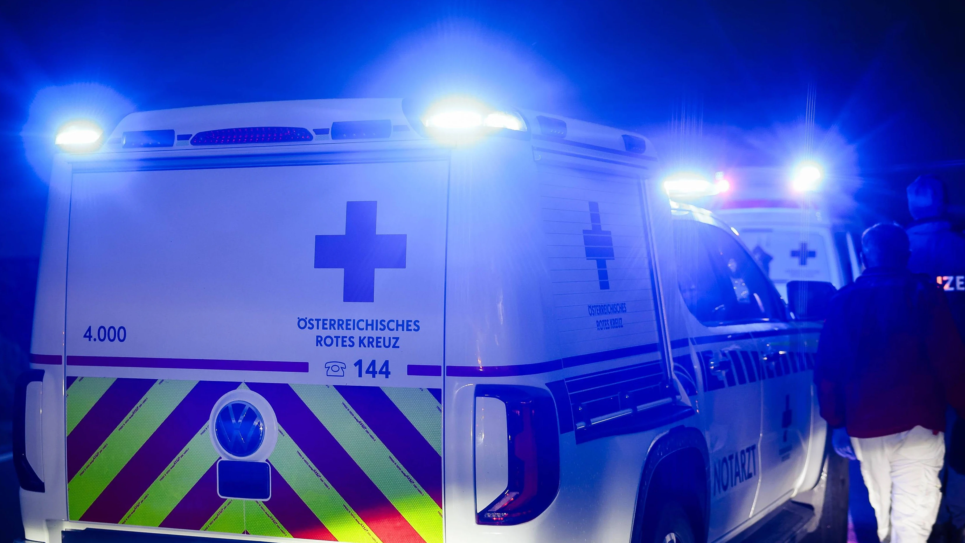 01.10.2024, Burgkirchen, AUT, Unterwegs in Oberösterreich, Symbolbild, Themenbild, Verschiedene Themenbilder, Unfall, Einsatzkräfte, Polizei, Rettung, Notarzt, Feuerwehr, im Bild Einsatzwagen, Notarzt, Erste Hilfe, Notarztwagen, Das Bild zeigt ein Notarzt-Einsatzfahrzeug des Rettungsdienstes in Oberösterreich vom Stützpunkt Braunau. Das Fahrzeug ist ein weißer Volkswagen mit auffälligen rot-gelben Markierungen und einem beleuchteten Blaulicht. Es ist auf einer Landstraße bei Regen zu sehen, Landstraße, Regen, Abenddämmerung, Unfallstelle, Rettung, Erste Hilfe, *** 01 10 2024, Burgkirchen, AUT, On the road in Upper Austria, symbol picture, theme picture, various theme pictures, accident, emergency services, police, rescue, emergenc