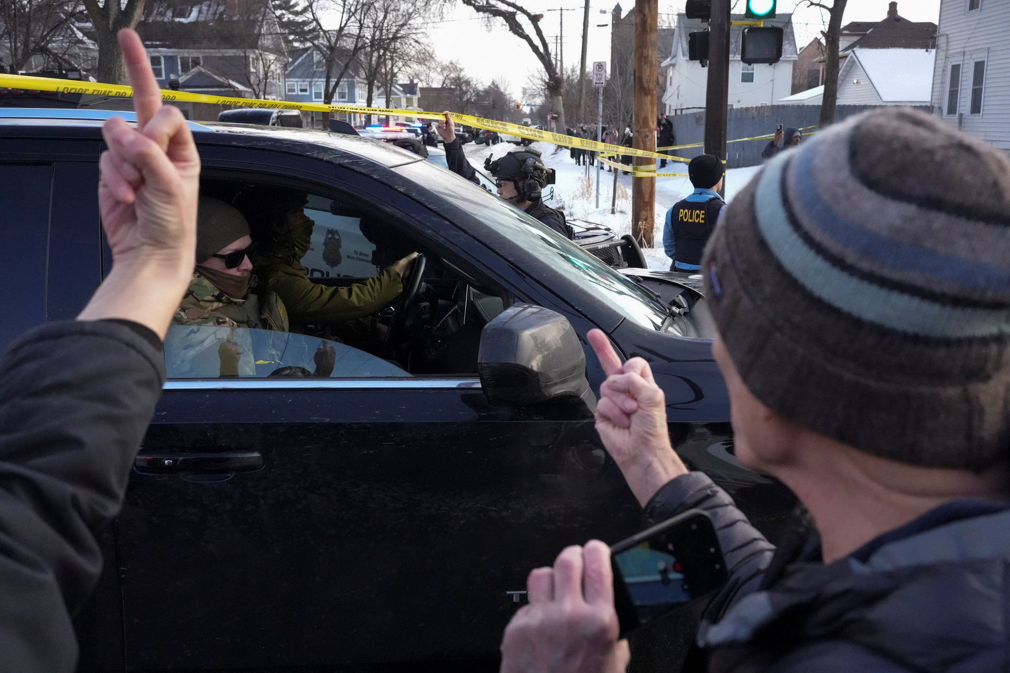 ICE-Beamte fahren an einer aufgebrachten Menge vorbei