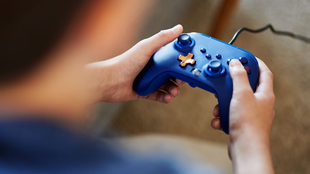 a closeup of a blue controller in the hands of a boy