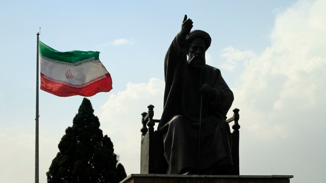 Eine iranische Flagge weht neben Ruhollah Khomeini, dem Gründer und ersten Obersten Führer der islamischen Republik Iran. (Symbolbild)