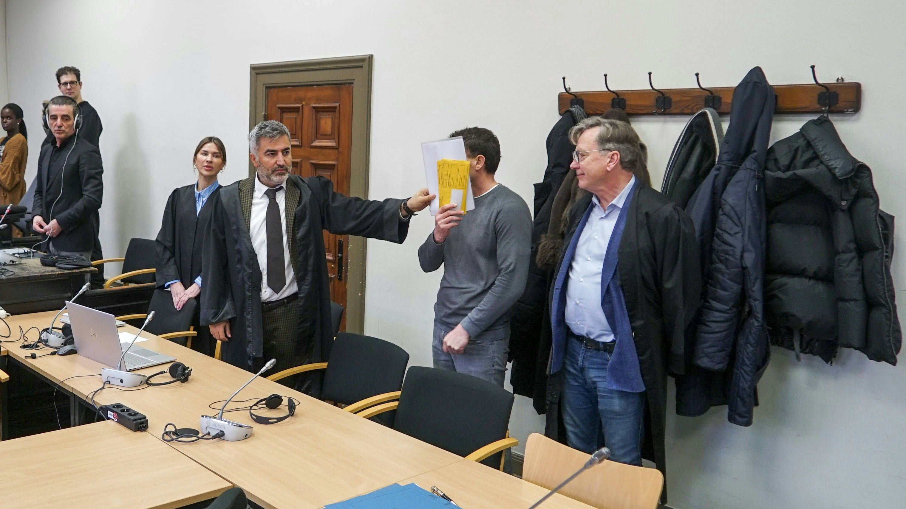 Der Angeklagte versucht, sein Gesicht mit seiner Gerichtsvorladung zu verbergen.