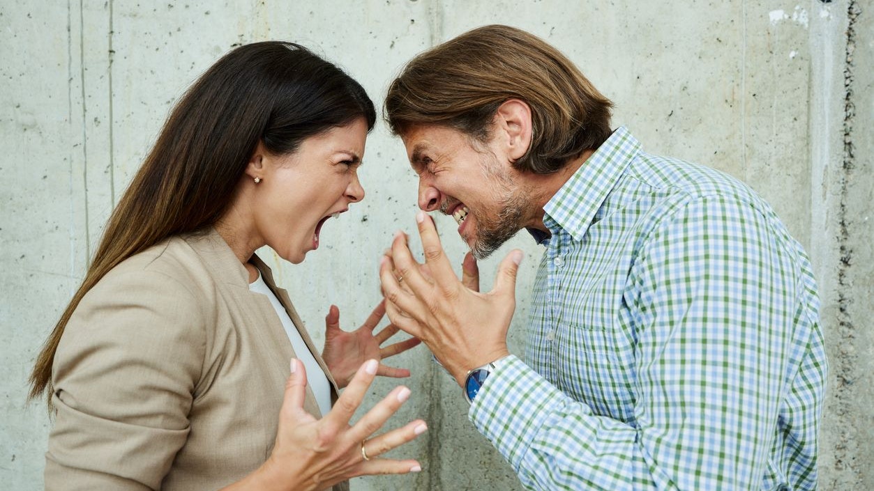 Displeased business colleagues having a fight against the wall in the office.