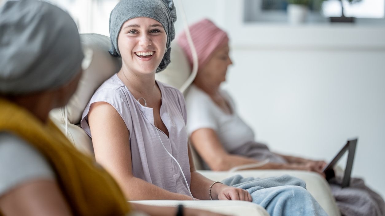 A group of cheerful patients undergoing chemotherapy treatment while sharing smiles and comfort in a bright and supportive healthcare setting.