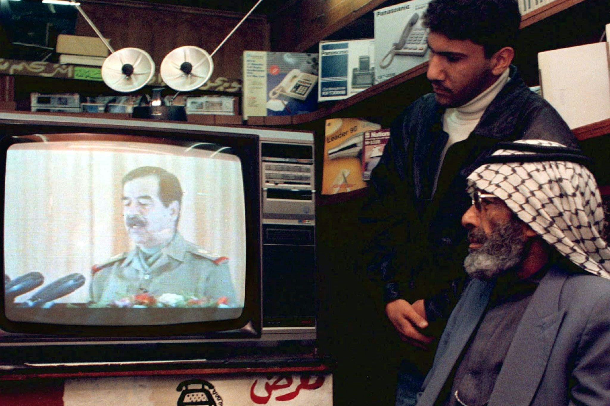 Ein Ladenbesitzer und sein Sohn verfolgen eine Fernsehansprache des irakischen Präsidenten Saddam Hussein