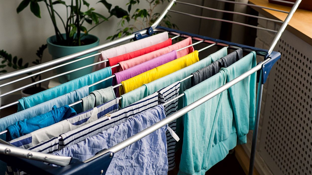 Laundry day Rainbow color clothes hanging on washing line to dry indoors home.