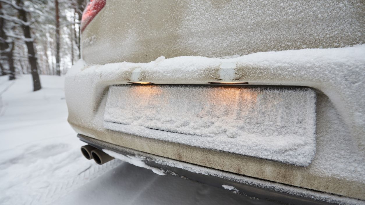 The license plate on the car is hidden by the snow.