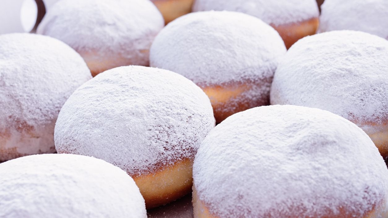 Jelly filled doughnuts with powdered sugar on a white background