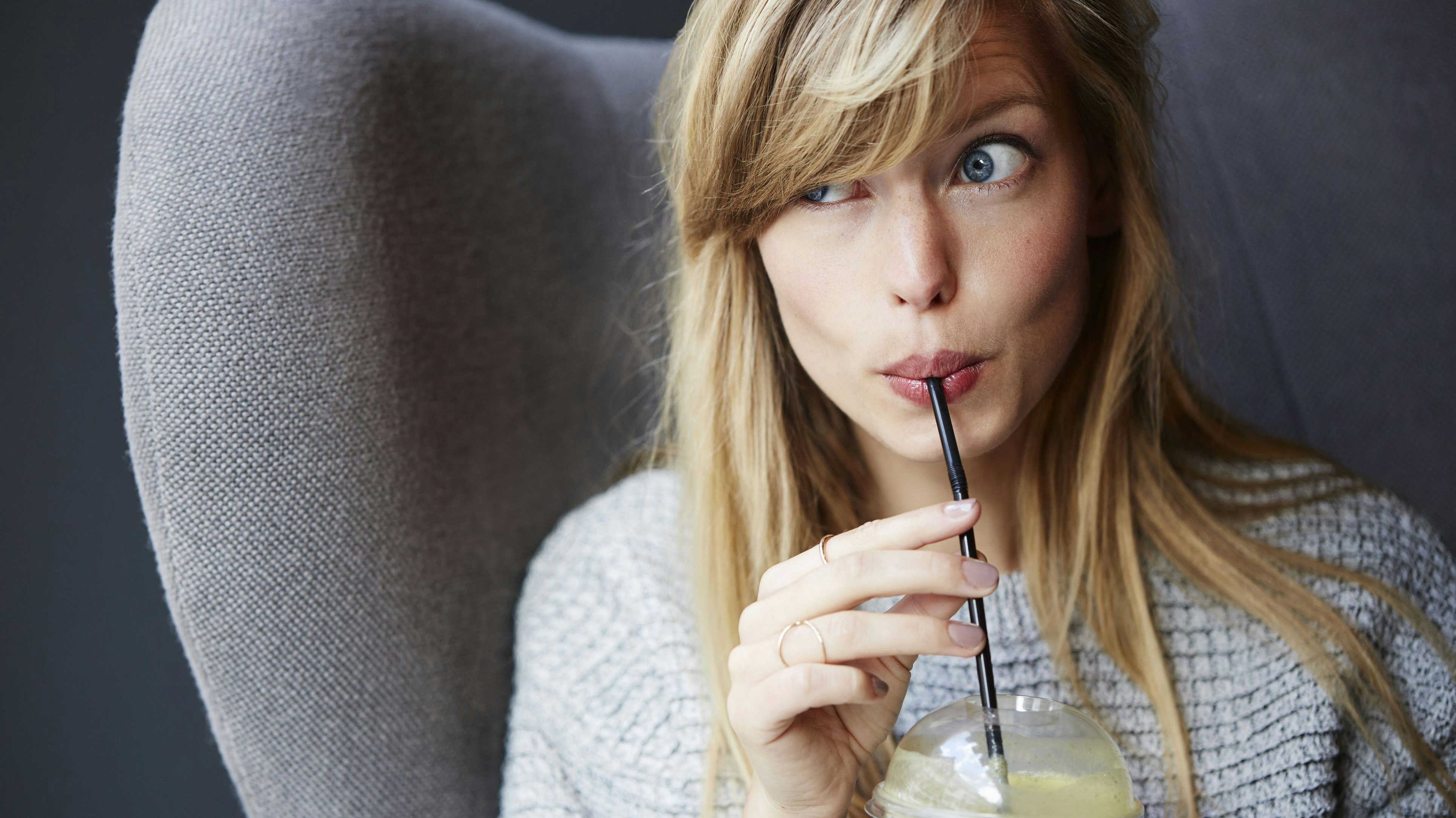 Frau trinkt Smoothie mit Strohhalm...