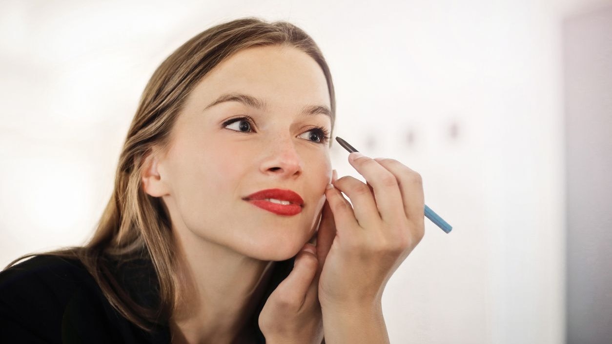 beautiful woman putting make-up on looking in the mirror