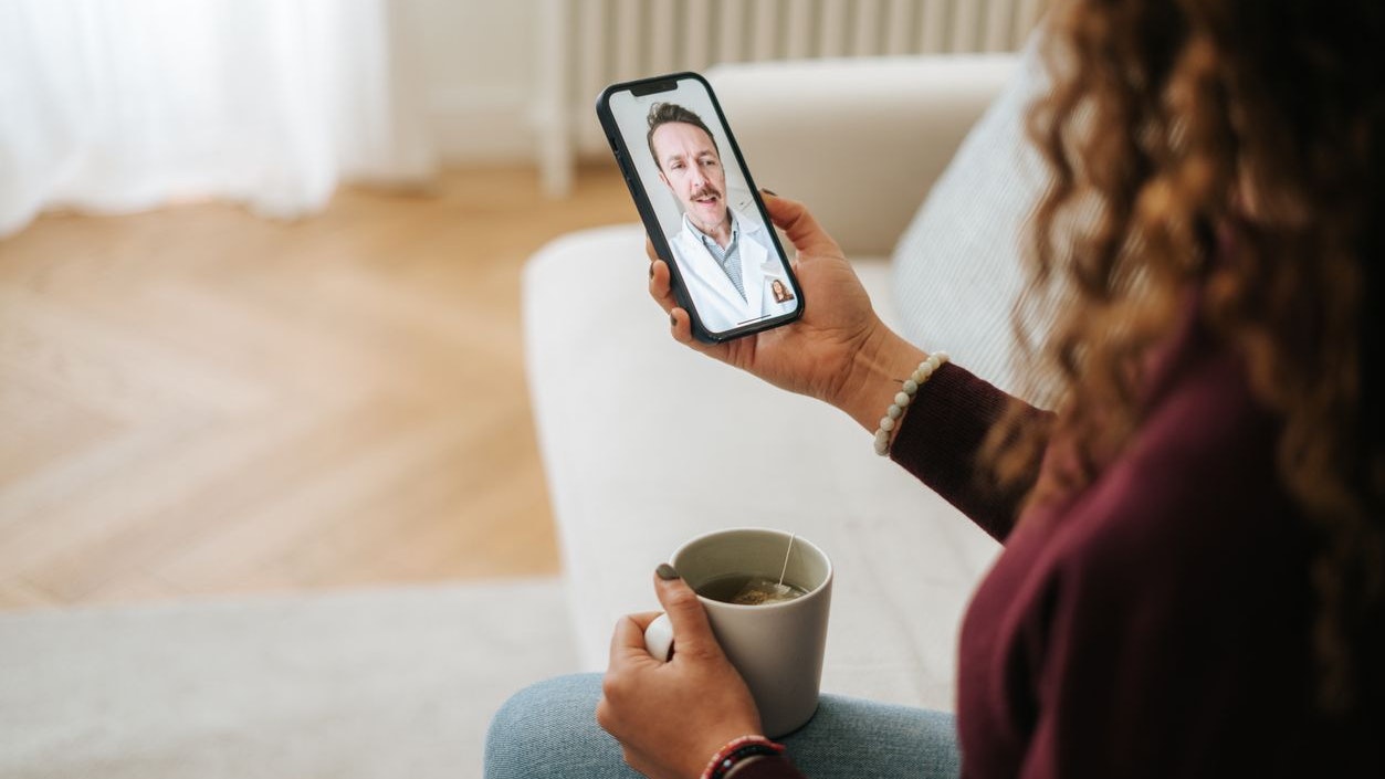 Woman using phone talk to doctor sitting on sofa