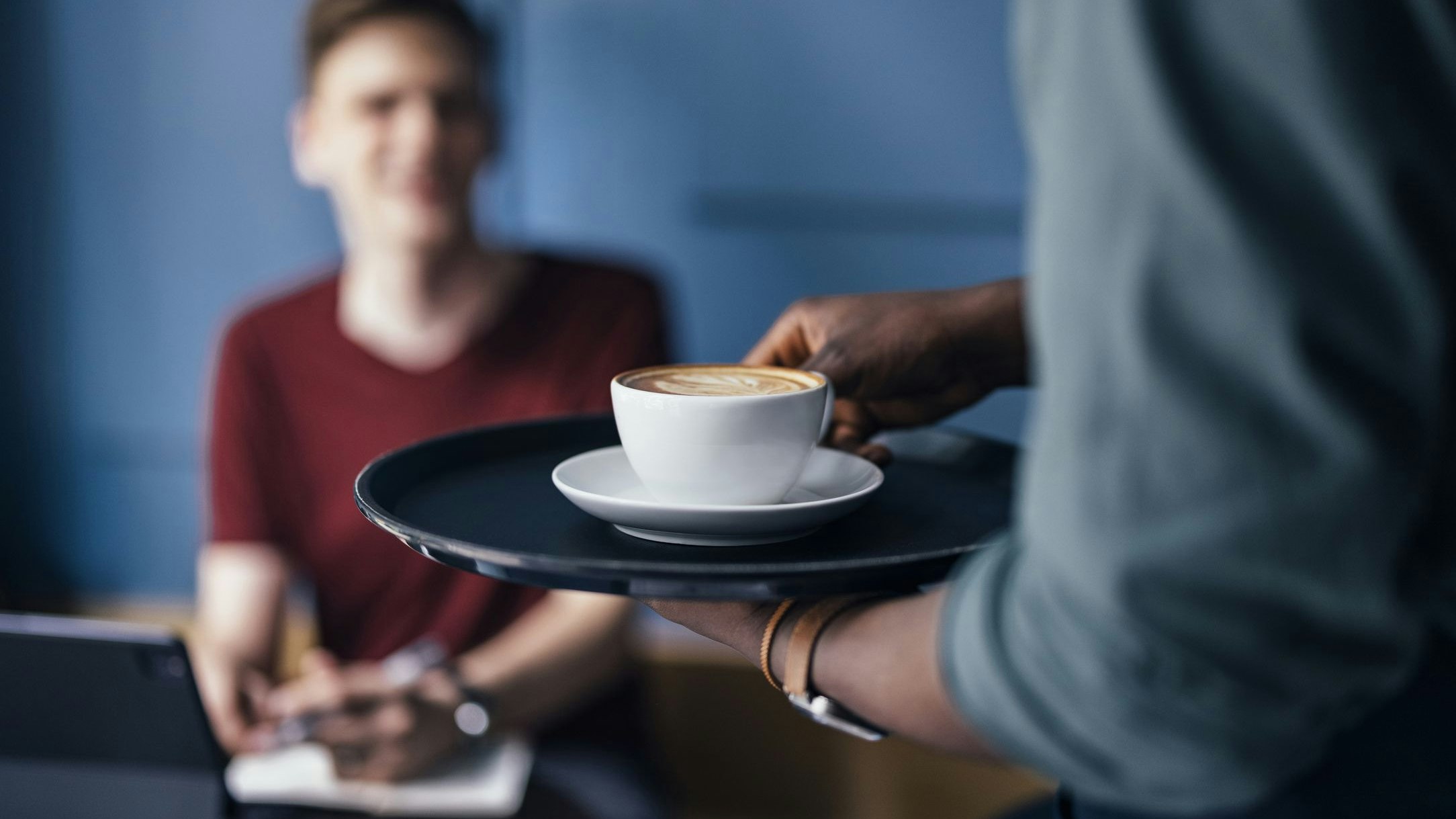 Unrecognizable African-American barista bringing an order to customer in a cafeteria