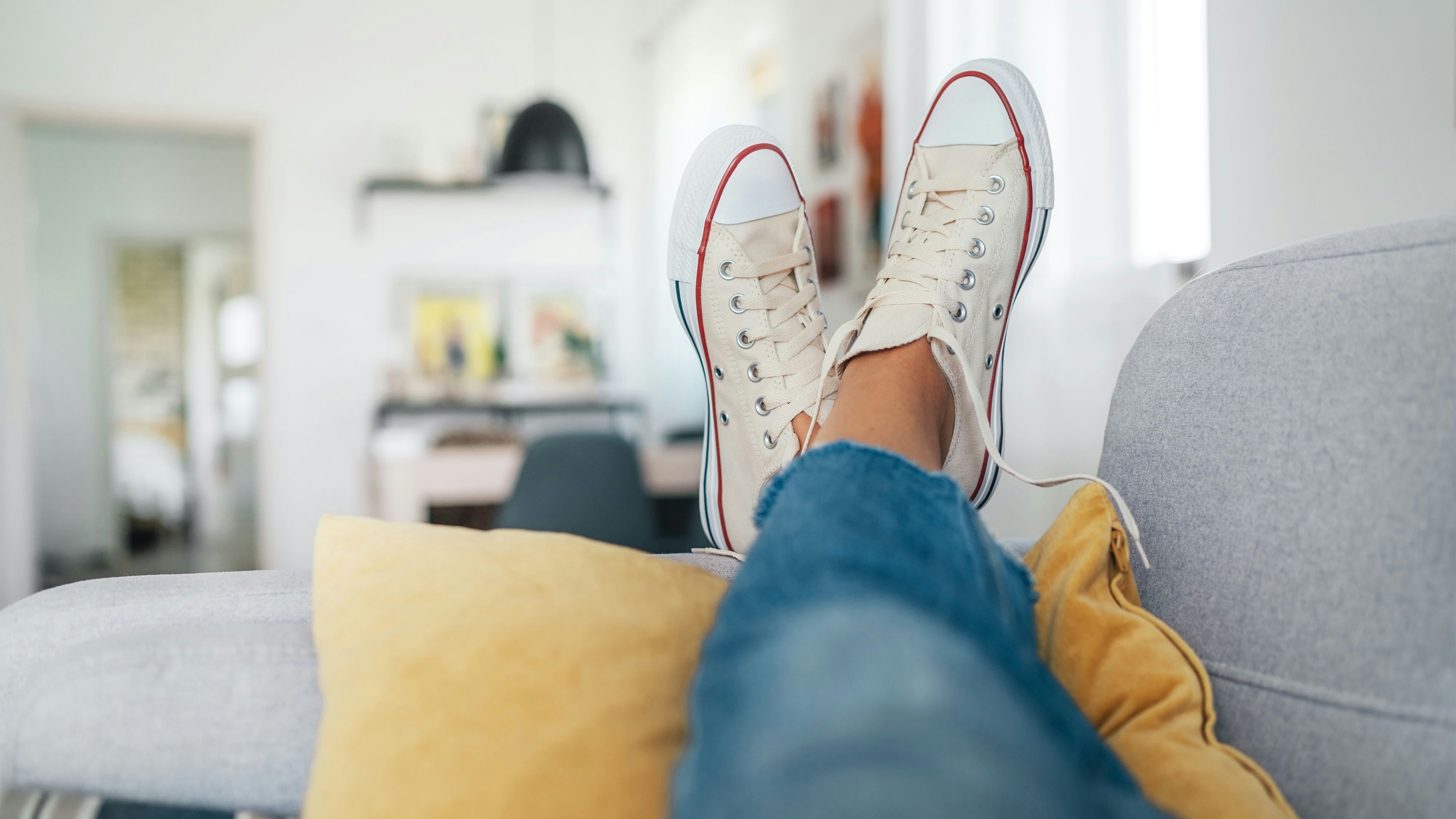 Frau trägt Sneaker auf dem Sofa...