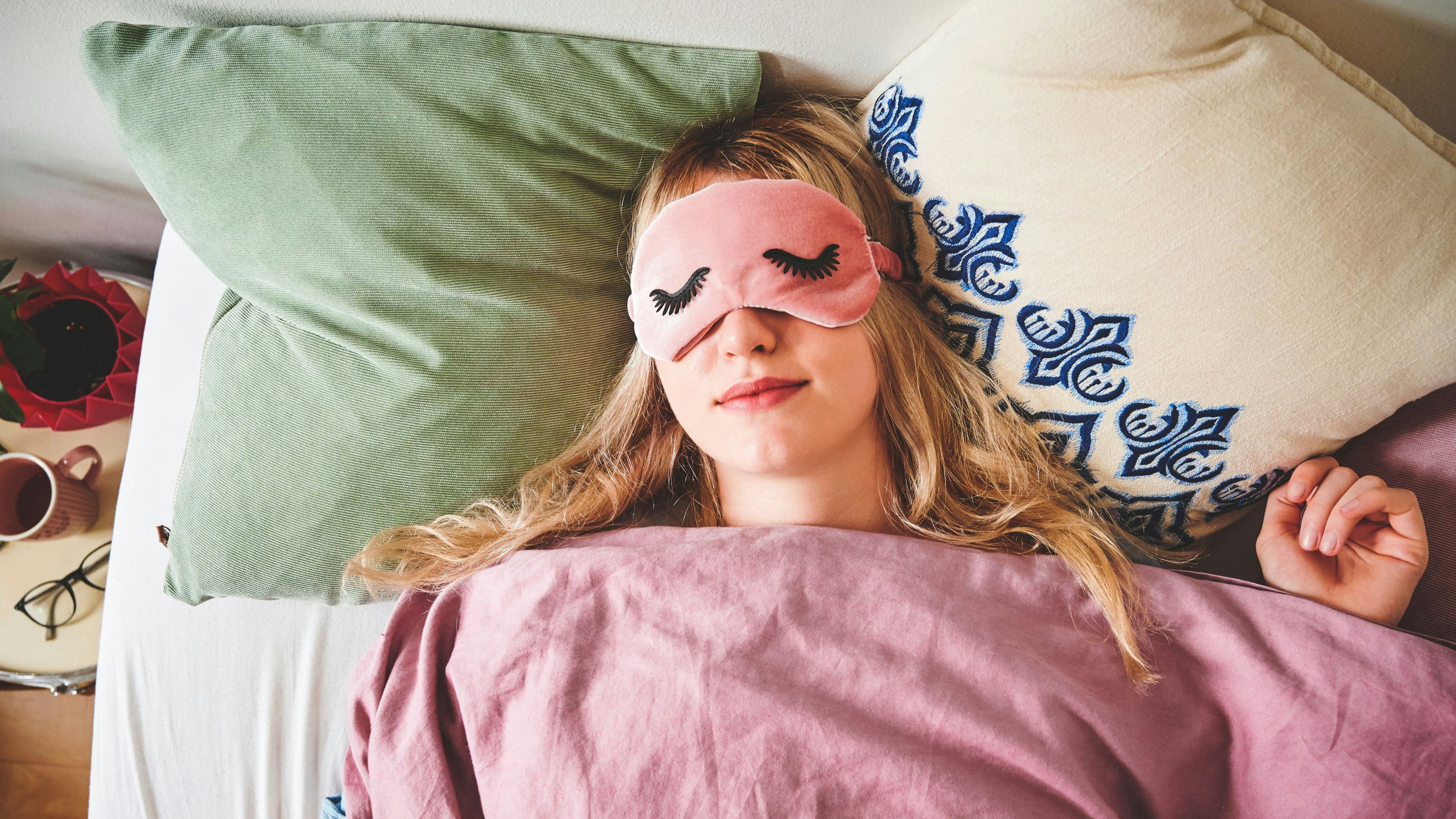 Frau schläft mit Schlafmaske im Bett...