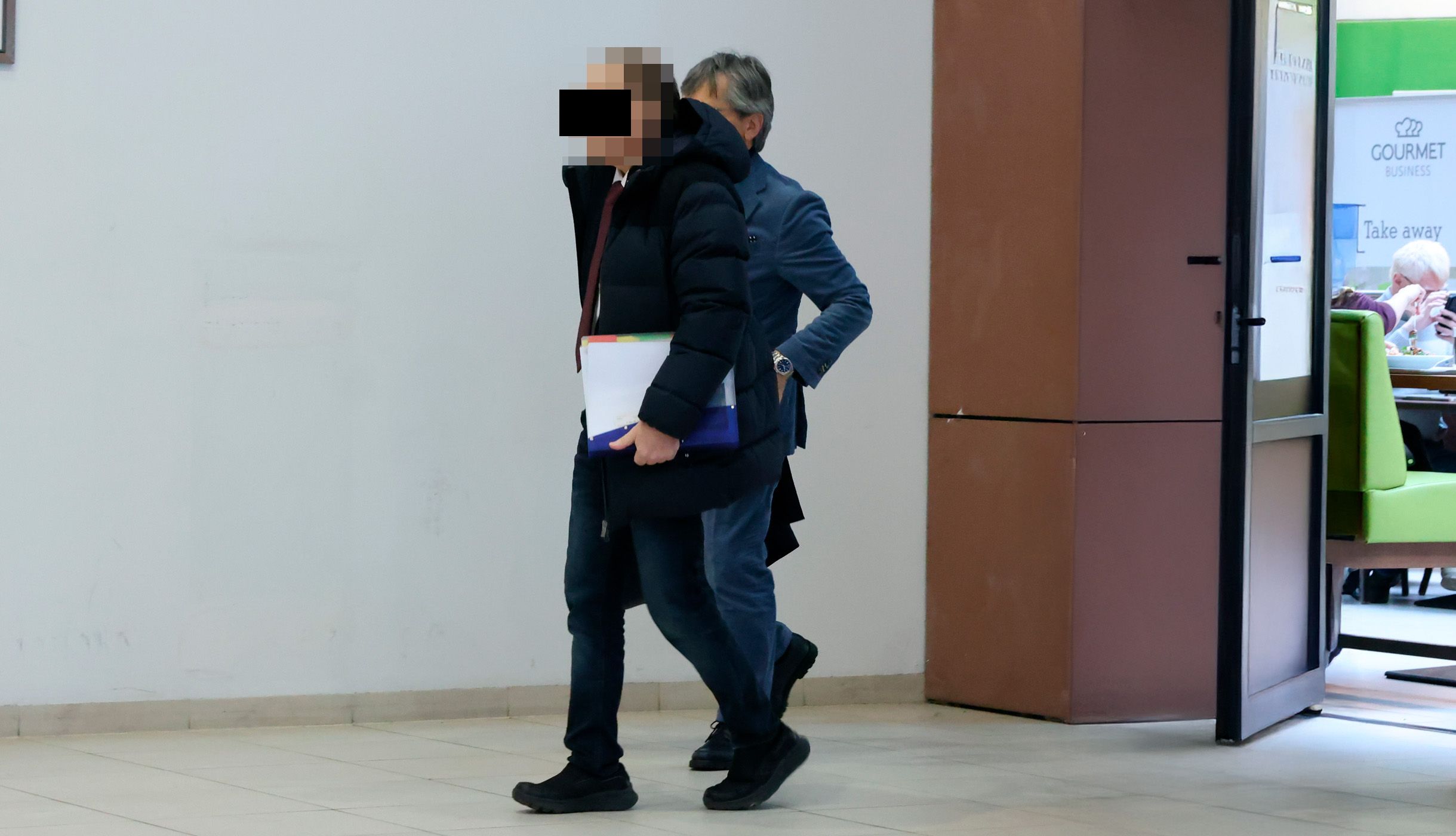 Der Anwalt mit seinem Anwalt (dahinter) im Eingangsbereich des Gerichtsgebäudes.