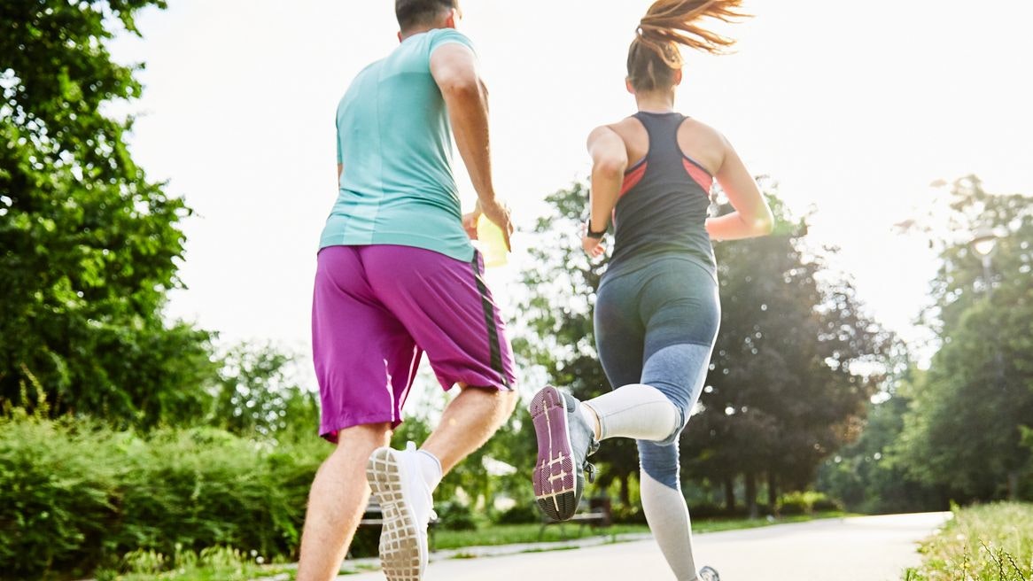 Portrait of a young couple running and exercising in a park outdoors