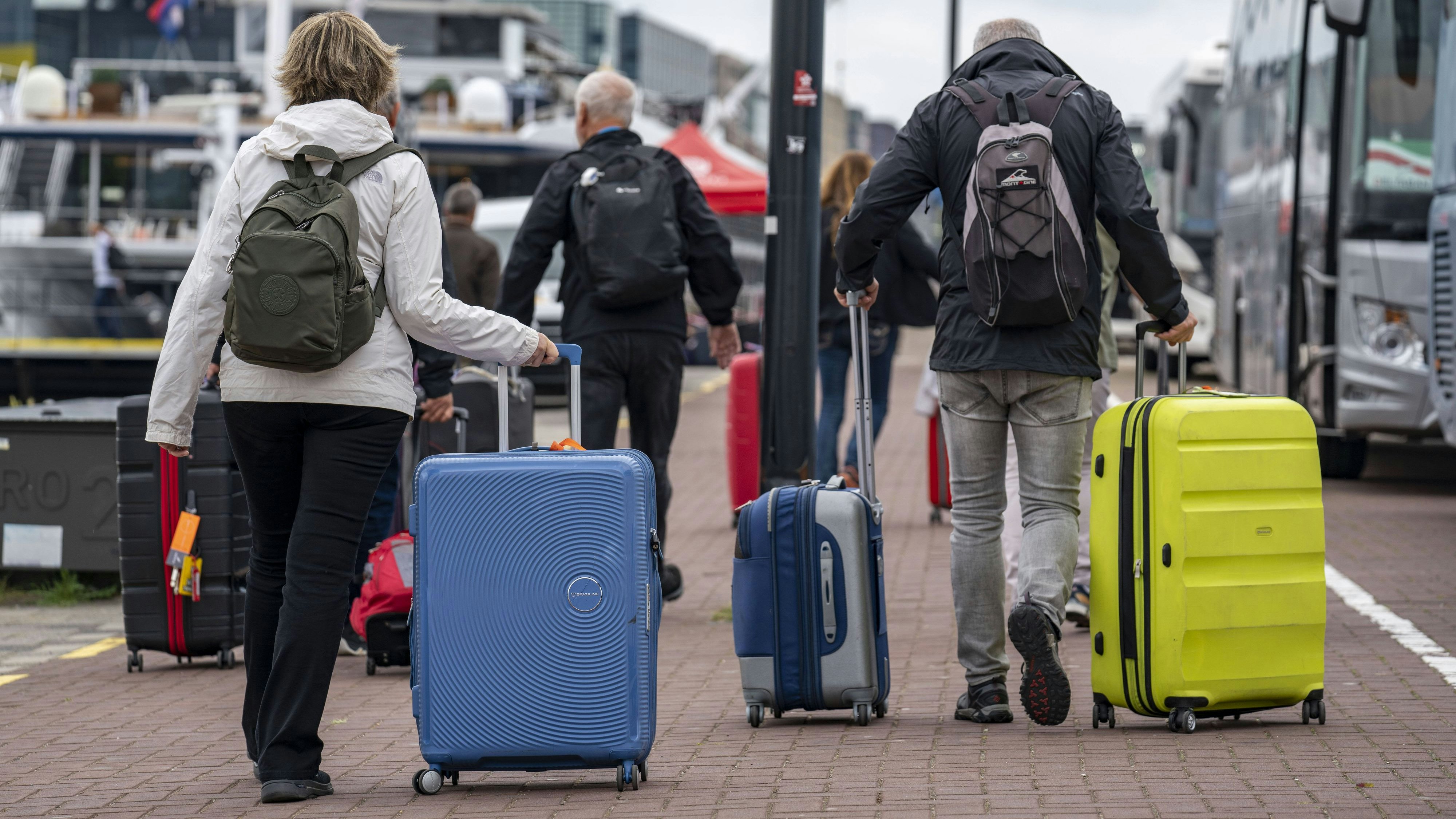 Reisende auf dem Weg zu einem Flusskreuzfahrtschiffe am Kai der Ij, transportieren ihr Gepäck, Rollkoffer, vom Hauptbahnhof zu Schiff, Amsterdam, Niederlande, Kreuzfahrt *** Travelers on the way to a river cruise ship on the quay of the Ij, transporting their luggage, rolling suitcases, from the central station to ship, Amsterdam, Netherlands, cruise