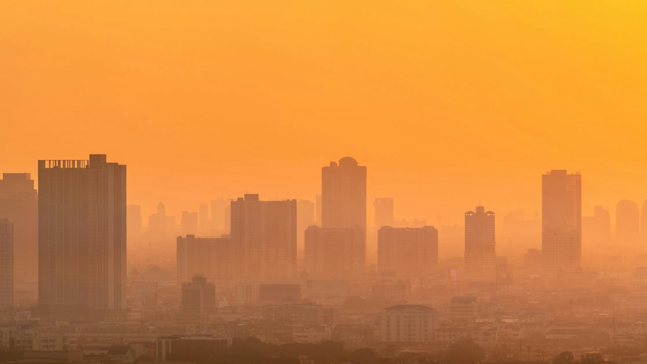 Air pollution. Smog and fine dust of pm2.5 covered city in the morning with orange sunrise sky. Cityscape with polluted air. Dirty environment. Urban toxic dust. Unhealthy air. Urban unhealthy living.