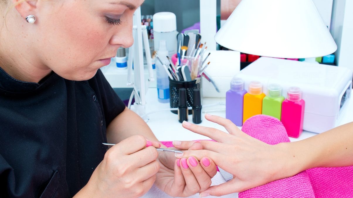 woman hand on manicure treatment with cuticle knife in beauty salon