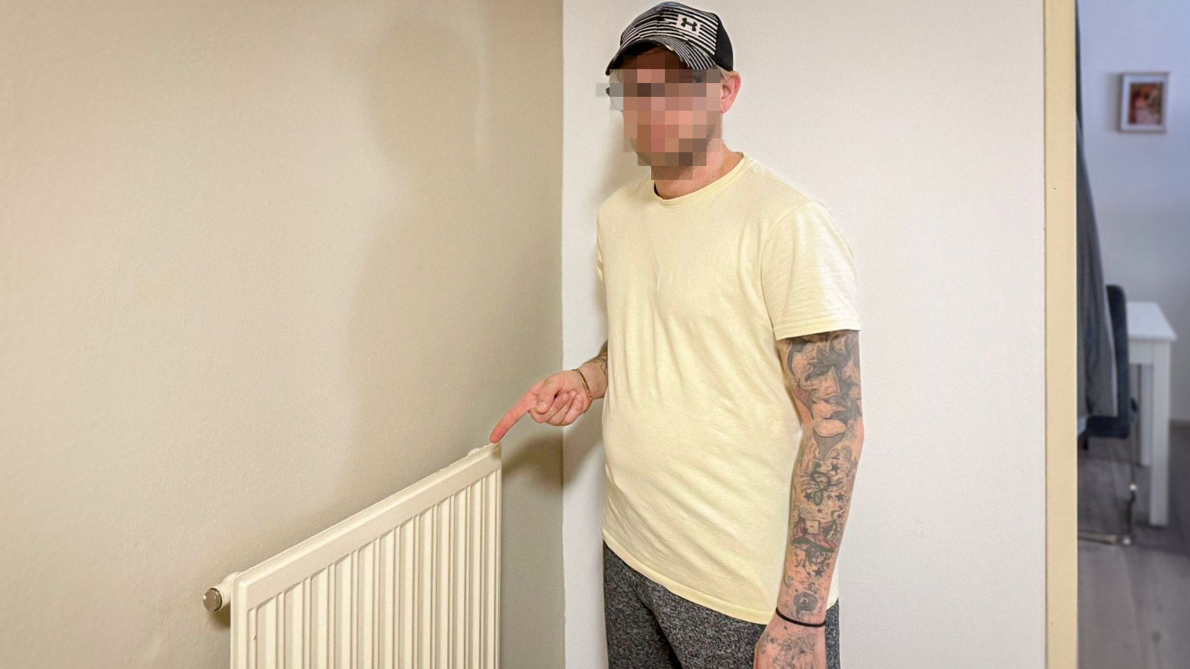 Christian V. zeigt auf einen Heizkörper im Vorzimmer seiner Genossenschaftswohnung.