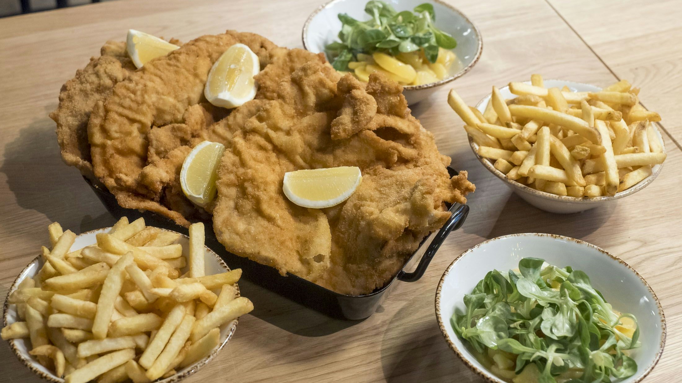 Beim Schnitzel-Inferno werden XXL-Schnitzel mit French Fries und Erdäpfel-Vogerlsalat serviert.