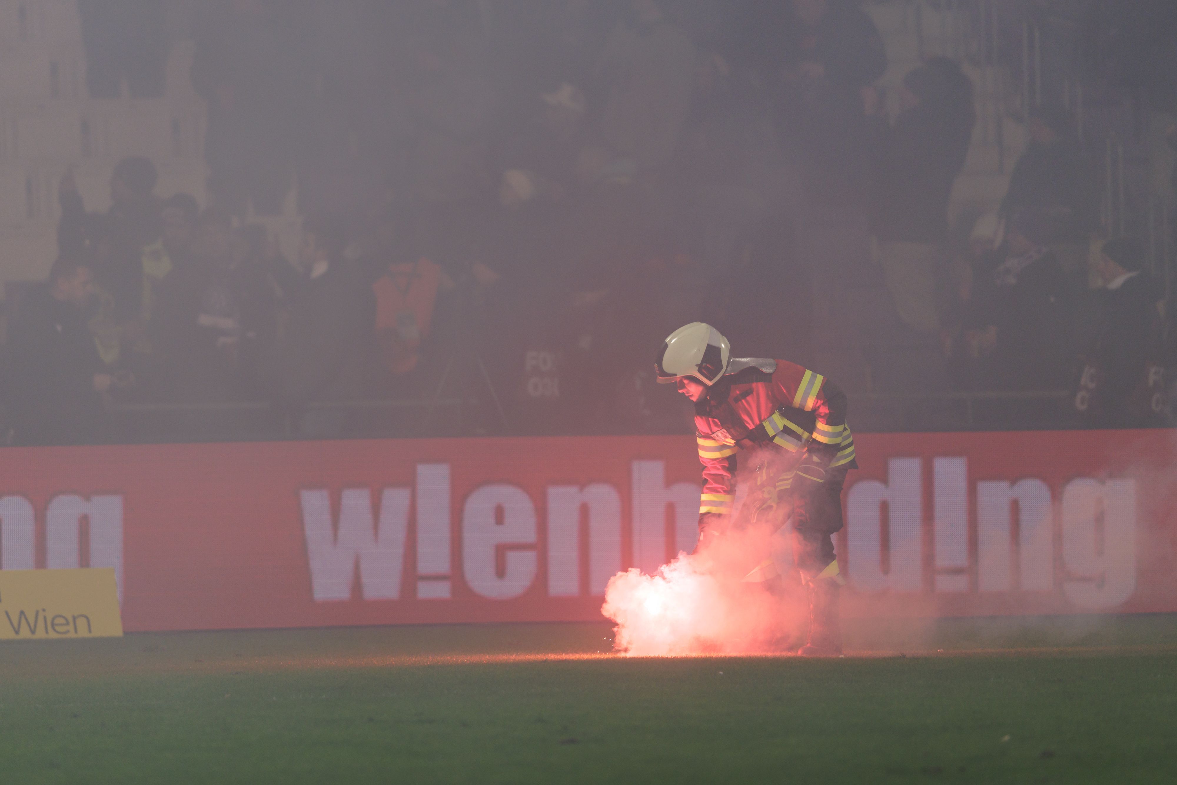 Ein Feuerwehrmann beseitigt eine Bengalische Fackel vom Spielfeld.