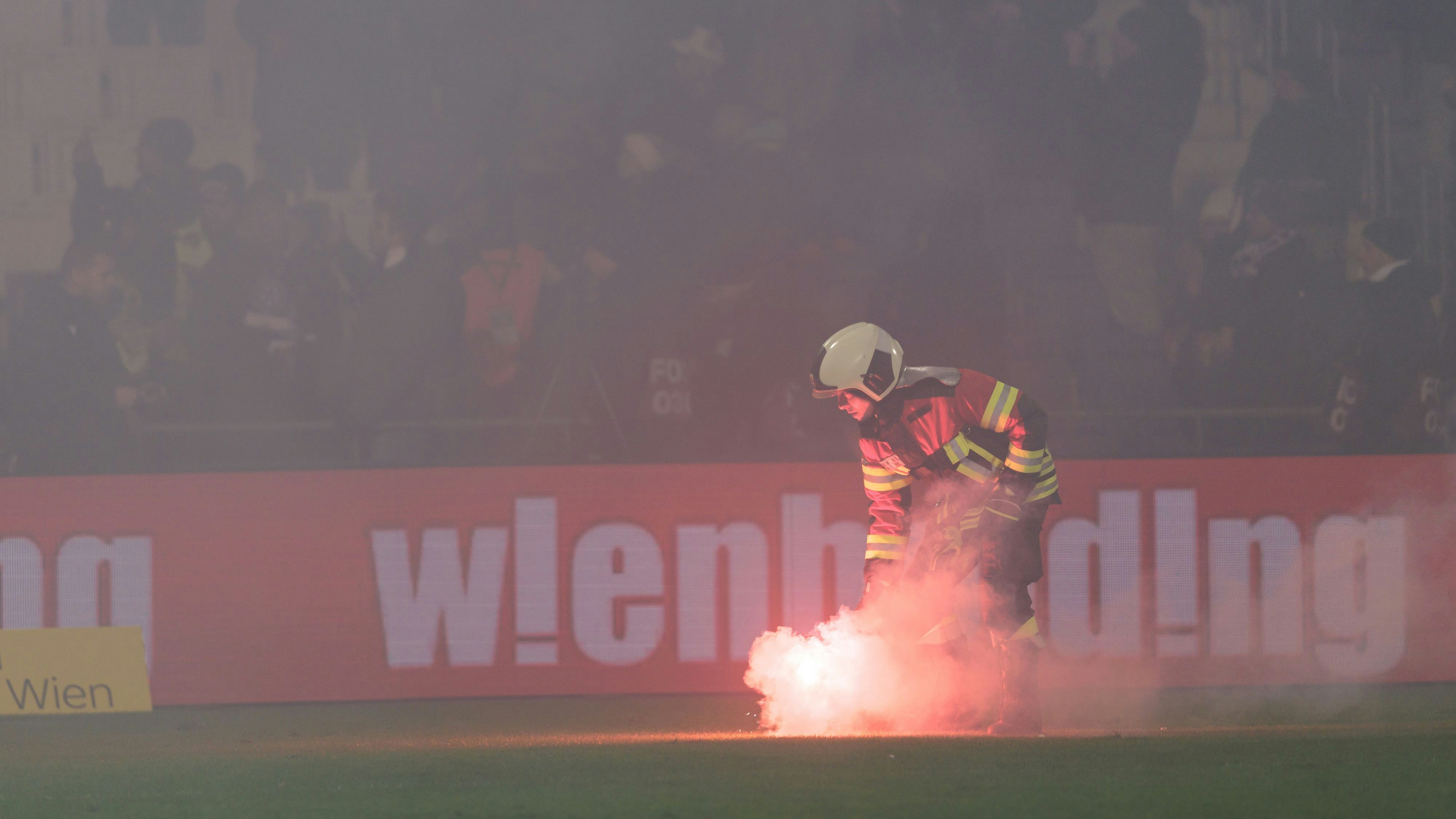 Ein Feuerwehrmann beseitigt eine Bengale vom Spielfeld.