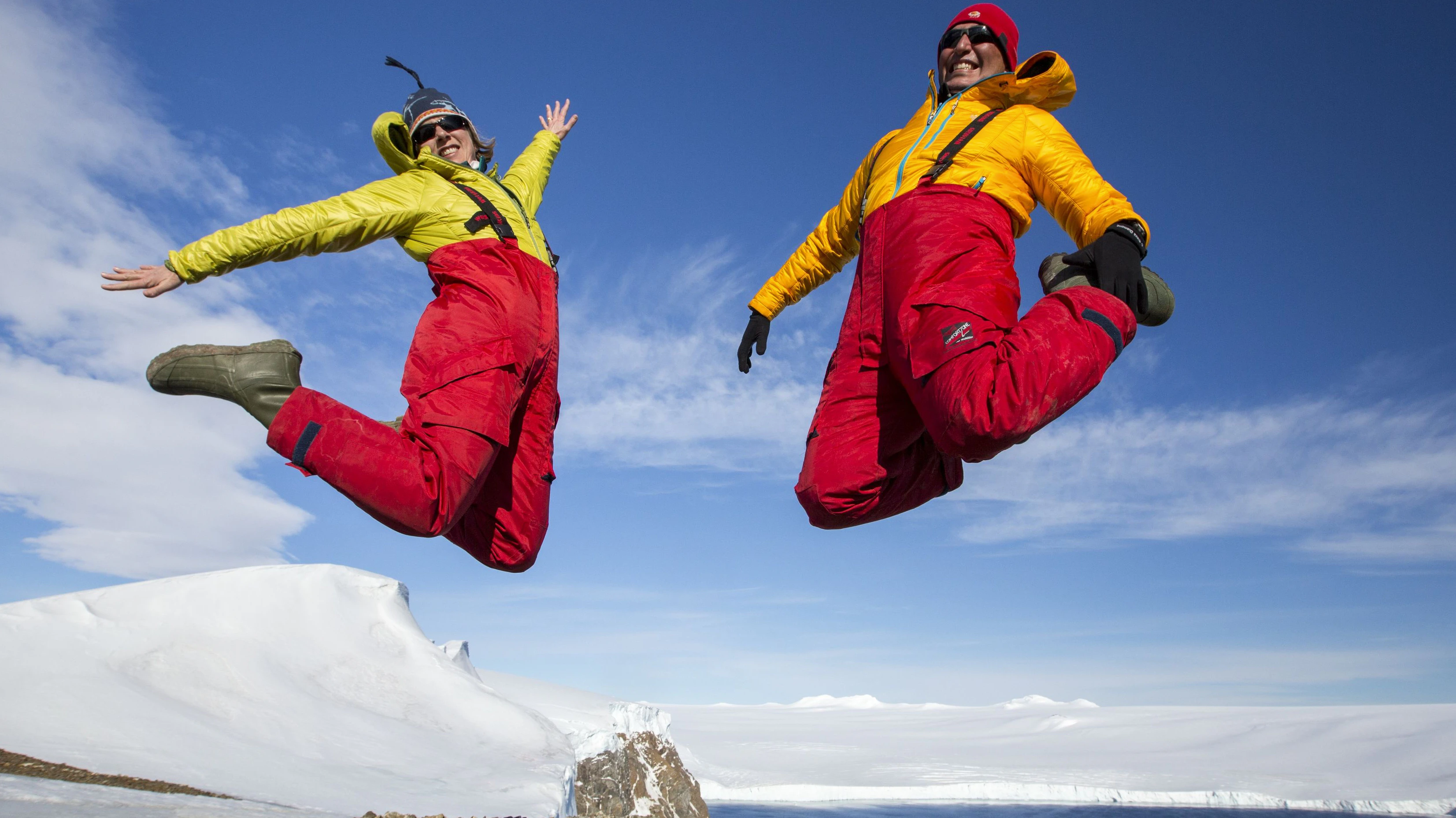 A man and woman jumping for joy from an expedition cruise on Joinville Island just off the Antarctic Peninsular. The Peninsular is one of the fastest warming places on the planet.