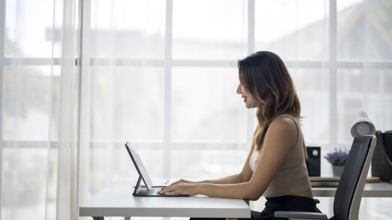 Young asian businesswoman working from home, typing on a tablet in her bright and airy home office