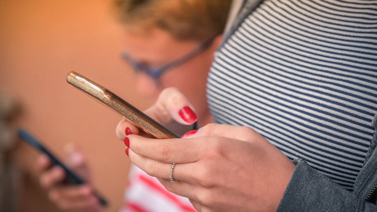 Mother and son watching smart mobile phones. Close-up on the hands holding smartphone.  Generation x and z addicted to new technology trends. Concept of technology, youth and social media friendship.