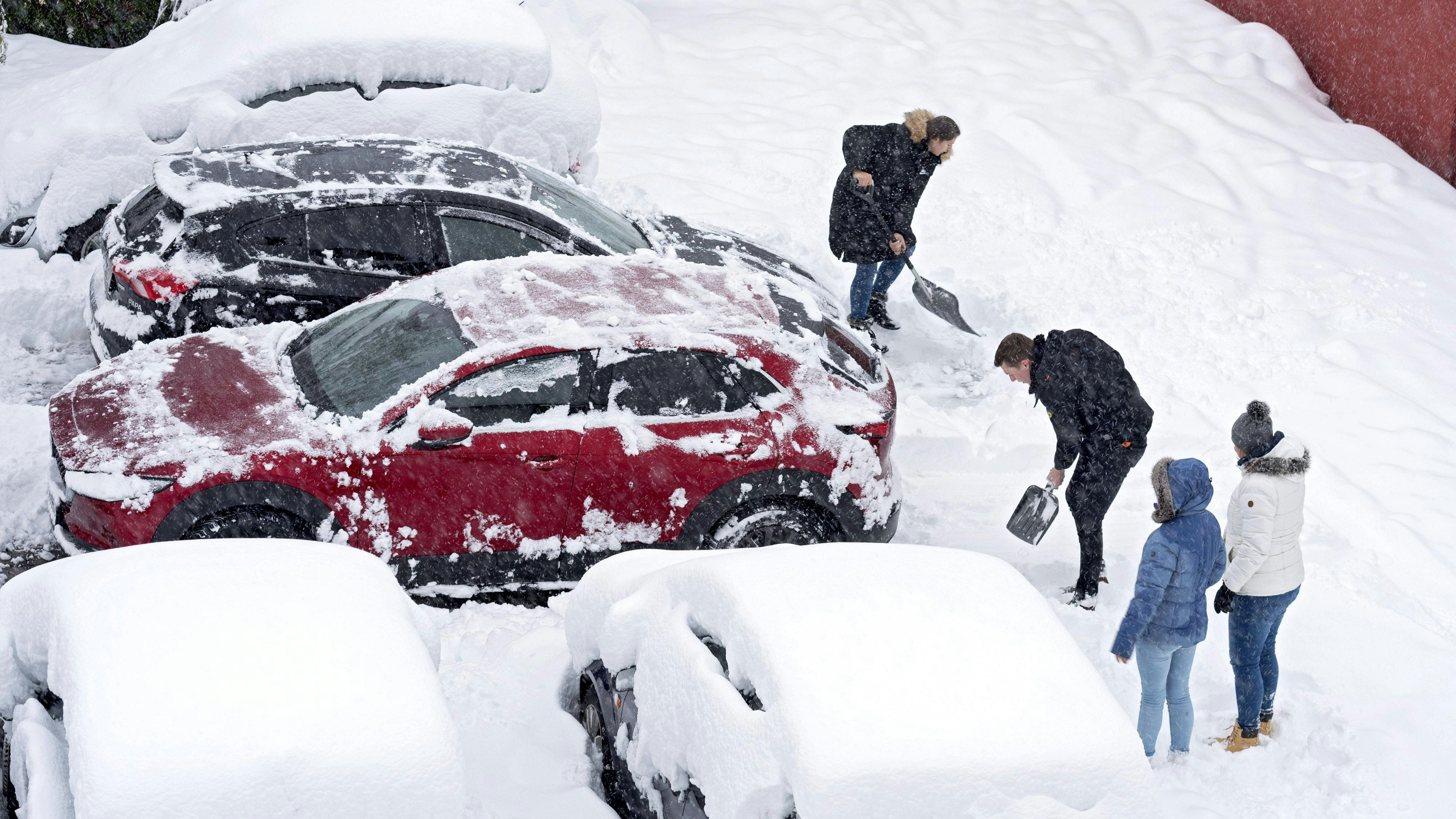 Autofahrer befreien ihre Fahrzeuge vom Schnee.