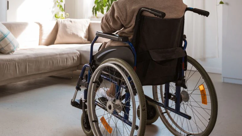 Back view of lonely senior woman sitting in a wheelchair in her room.