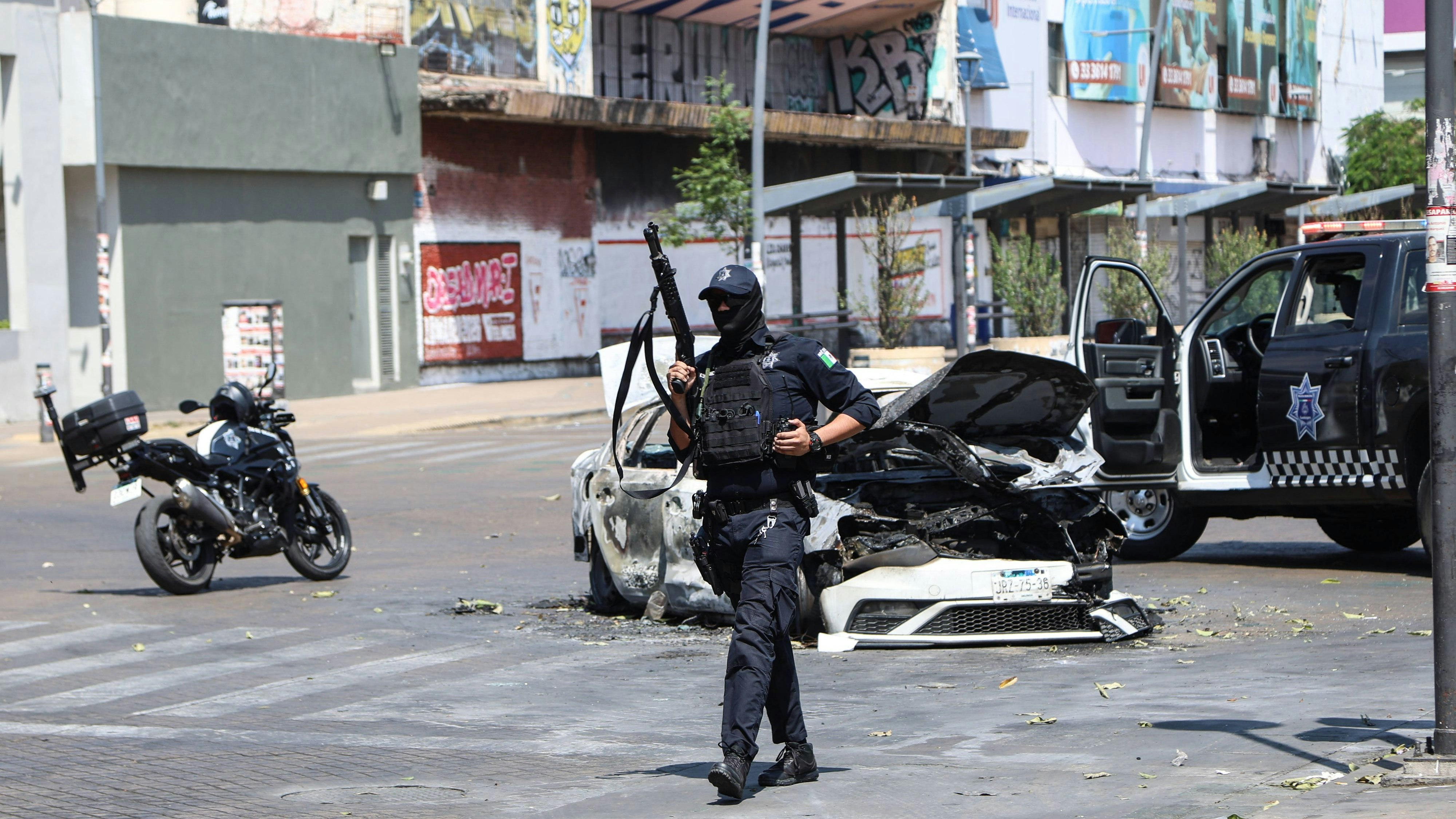 260223 -- JALISCO, Feb. 23, 2026 -- A policeman guards near a burnt car on a street in Guadalajara, capital of Jalisco state, Mexico, on Feb. 22, 2026. Mexican military forces killed Nemesio Oseguera Cervantes, alias El Mencho, the founder and leader of the Jalisco New Generation Cartel, during an operation on Sunday in the western state of Jalisco, according to local media reports. Since early Sunday, a heavy deployment of federal security forces has been reported across the region. Road blockades and vehicle burnings were recorded in Jalisco and neighboring states. Similar incidents involving torched vehicles and highway blockades were also reported in Tamaulipas and Oaxaca, causing disruption among residents. Photo by /Xinhua Spo PUBLICATIONxNOTxINxCHN