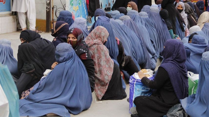 A number of poor Afghan women sitting in front of a bakery in capital Kabul to receive a piece of bread to feed their children.