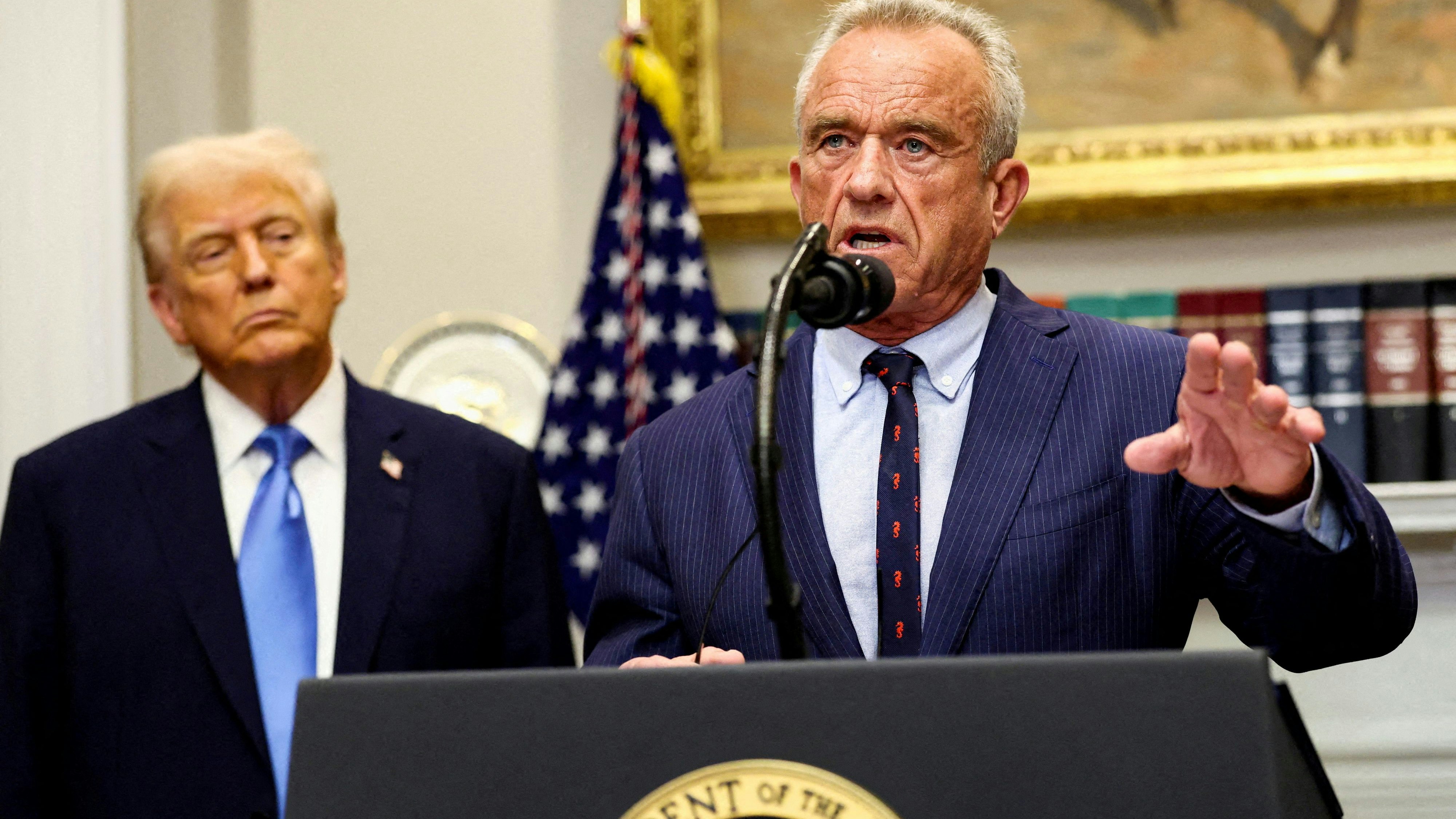 FILE PHOTO: U.S. Secretary of Health and Human Services Robert F. Kennedy Jr. delivers remarks while U.S. President Donald Trump listens during a press conference to announce a link between autism and childhood vaccines and the use of popular pain medication Tylenol for pregnant women and children, claims which are not backed by decades of science, at the White House, in Washington, D.C., U.S., September 22, 2025. REUTERS/Kevin Lamarque/File Photo