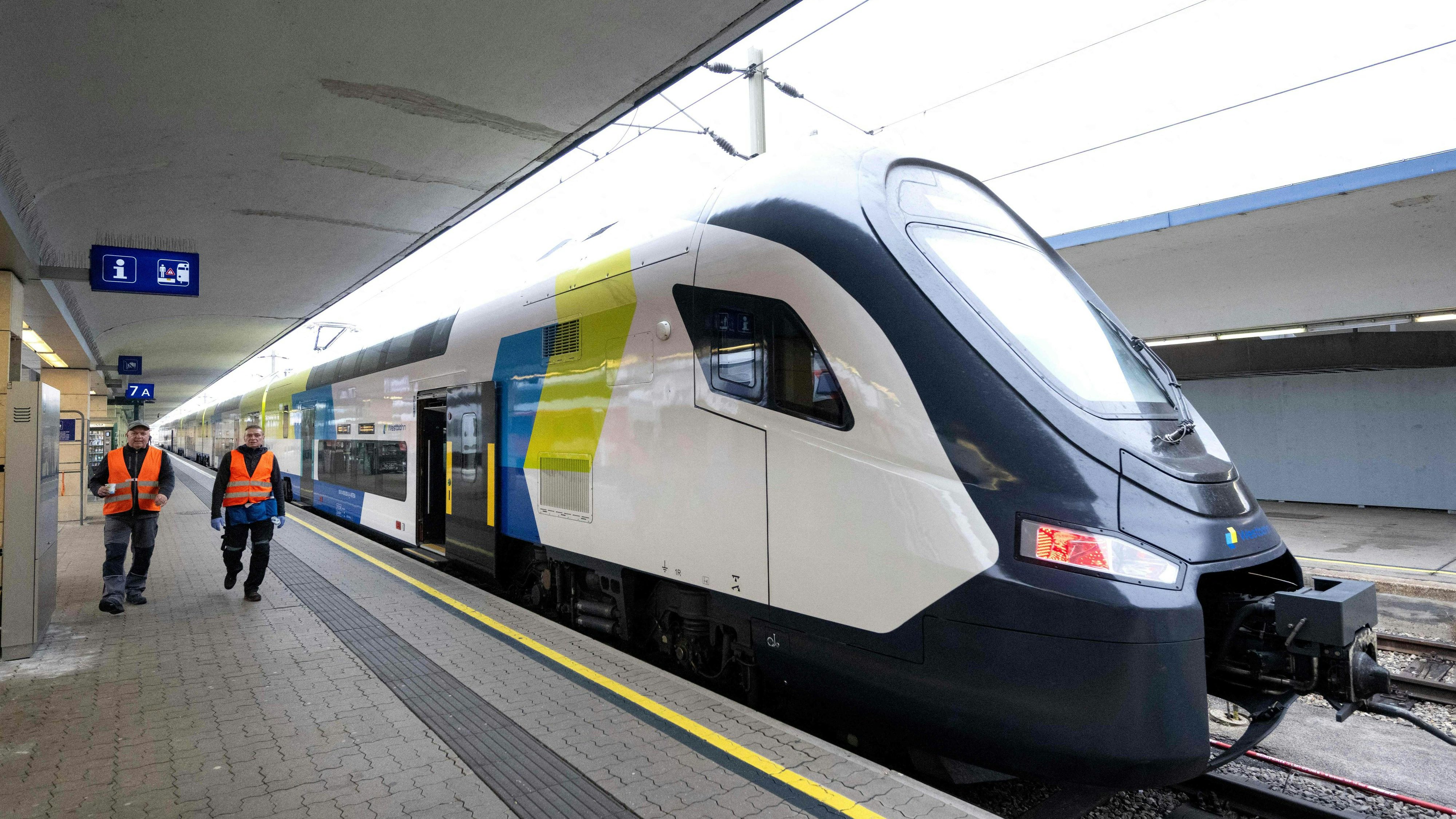 Railway workers walk past a new Westbahn train (made by CRRC in China) waiting for its departure from Westbahnhof (West Train Station) in Vienna, Austria on November 13, 2025. Austrian train operator Westbahn became the first in the EU to start using China-made trains for regular long-distance travel, which has sparked criticism in the Alpine nation. The first of four double-decker trains made by CRRC went into service, travelling from Vienna to Salzburg on November 12, 2025, a Westbahn spokesman told AFP. So far, the Czech Republic also has CRRC-made regional trains and Hungary has CRRC-made cargo jets, according to Westbahn. (Photo by Joe Klamar / AFP)