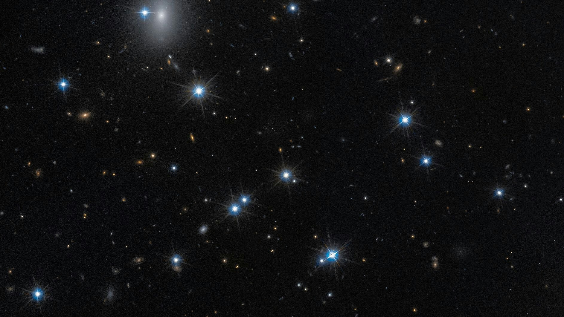 The low-surface-brightness galaxy CDG-2, shown in this image from the NASA/ESA Hubble Space Telescope, is dominated by dark matter and contains only a sparse scattering of stars. This galaxy is nearly invisible, but by using advanced statistical techniques, scientists identified it by searching for tight groupings of stars called globular clusters at the centre of this image. The Hubble observations include those from programme 15235 (W. Harris). [Image description: A field of space with a dozen white foreground stars and a number of small, yellow background galaxies.]