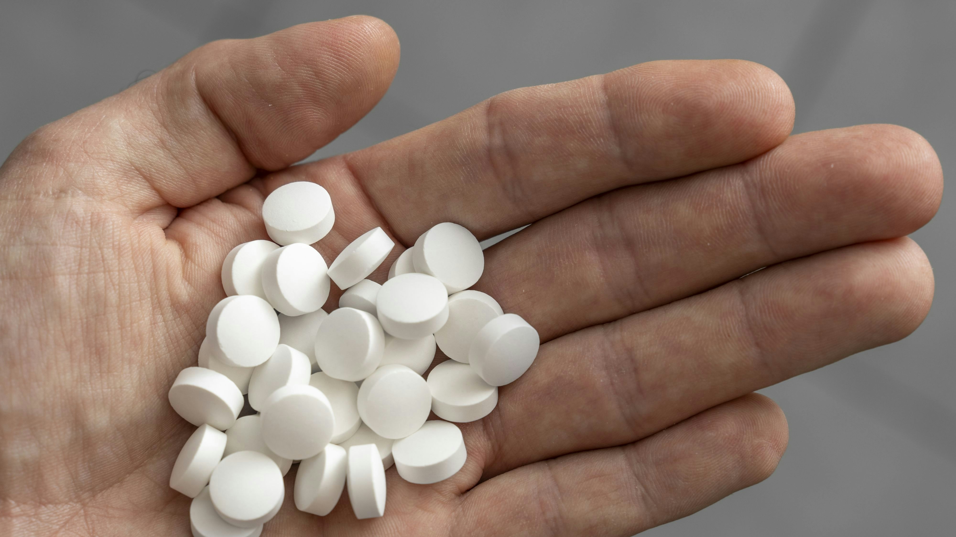 Ein Mann hat viele weiße Tabletten in der Hand. Medizin, Sucht und Drogen Konzept