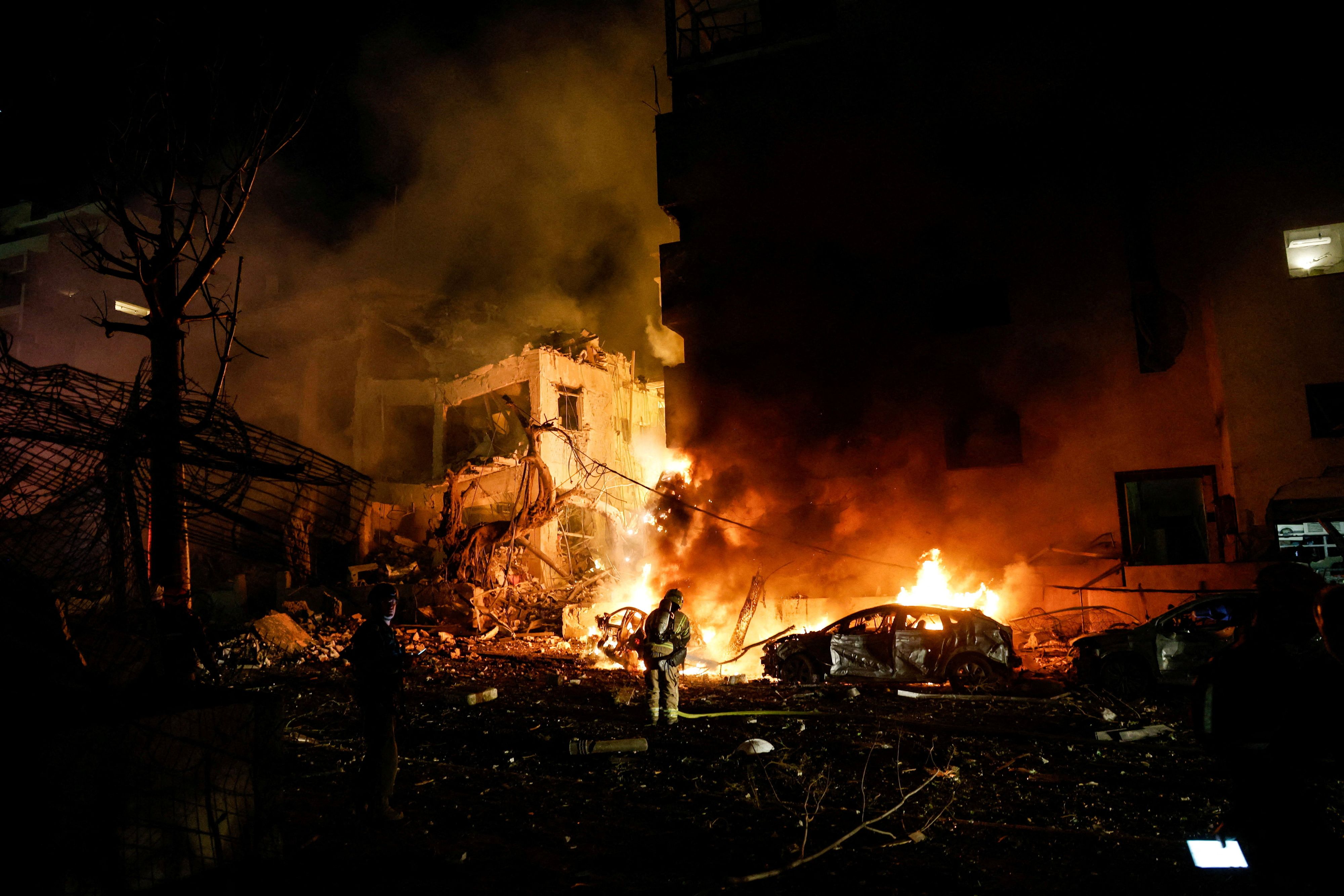 Israelische Feuerwehrleute bekämpfen einen Brand an einem Auto am Ort eines Raketeneinschlags in Tel Aviv
