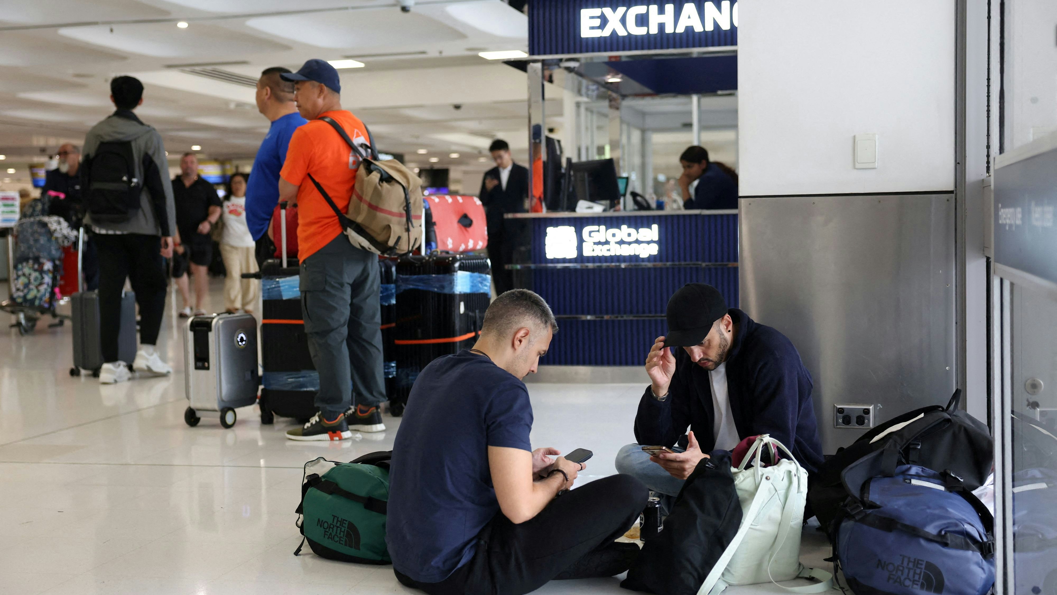 FILE PHOTO: Stranded travellers sit on the floor at Sydney Airport after their standby flight to Switzerland via Doha was cancelled, in Sydney, Australia, March 2, 2026. REUTERS/Hollie Adams/File Photo
