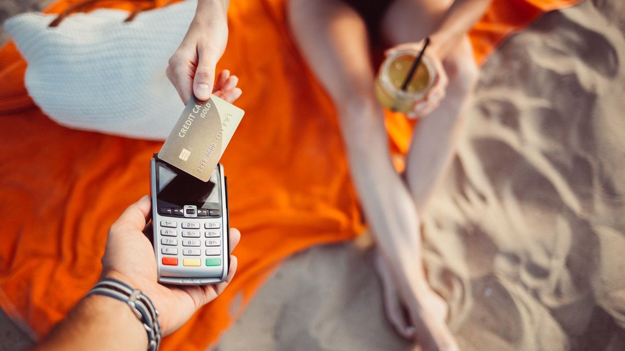 Above view of girl at the beach paying on the credit card reader