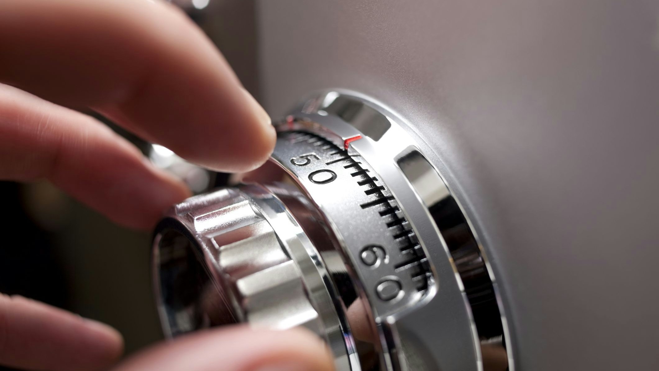 Hand opening an office or home safe, by operating the locking dial. Shallow depth of field. 