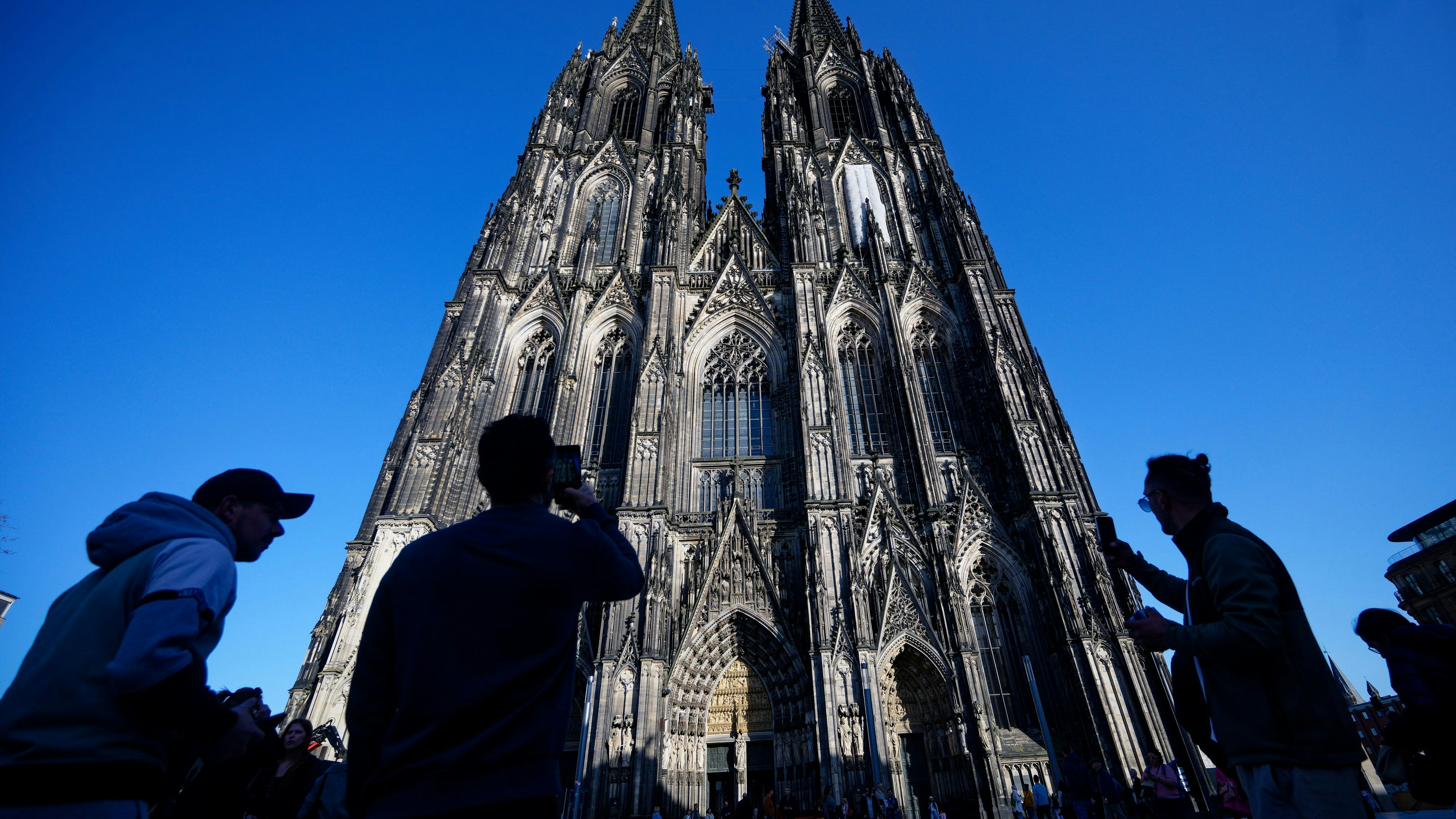 05 March 2026, North Rhine-Westphalia, Cologne: Tourists taking photos of Cologne Cathedral. In future, tourists will have to pay admission to Cologne Cathedral. This is to cover the increased costs for the care, protection and ongoing operation of the cathedral, as the cathedral chapter announced at a press conference Photo: Henning Kaiser/dpa