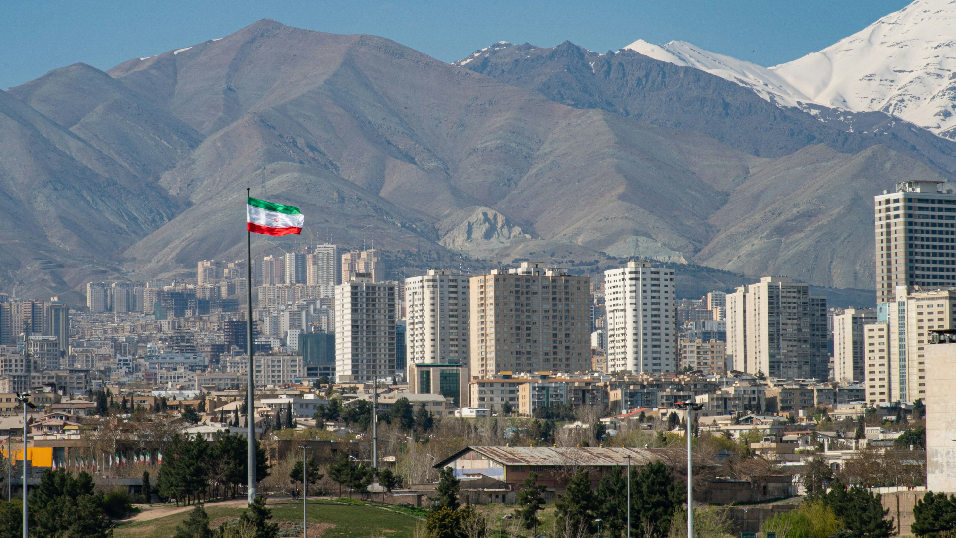 Panoramic view of the city of Tehran with the waving Iranian Flag and the mountains in the background