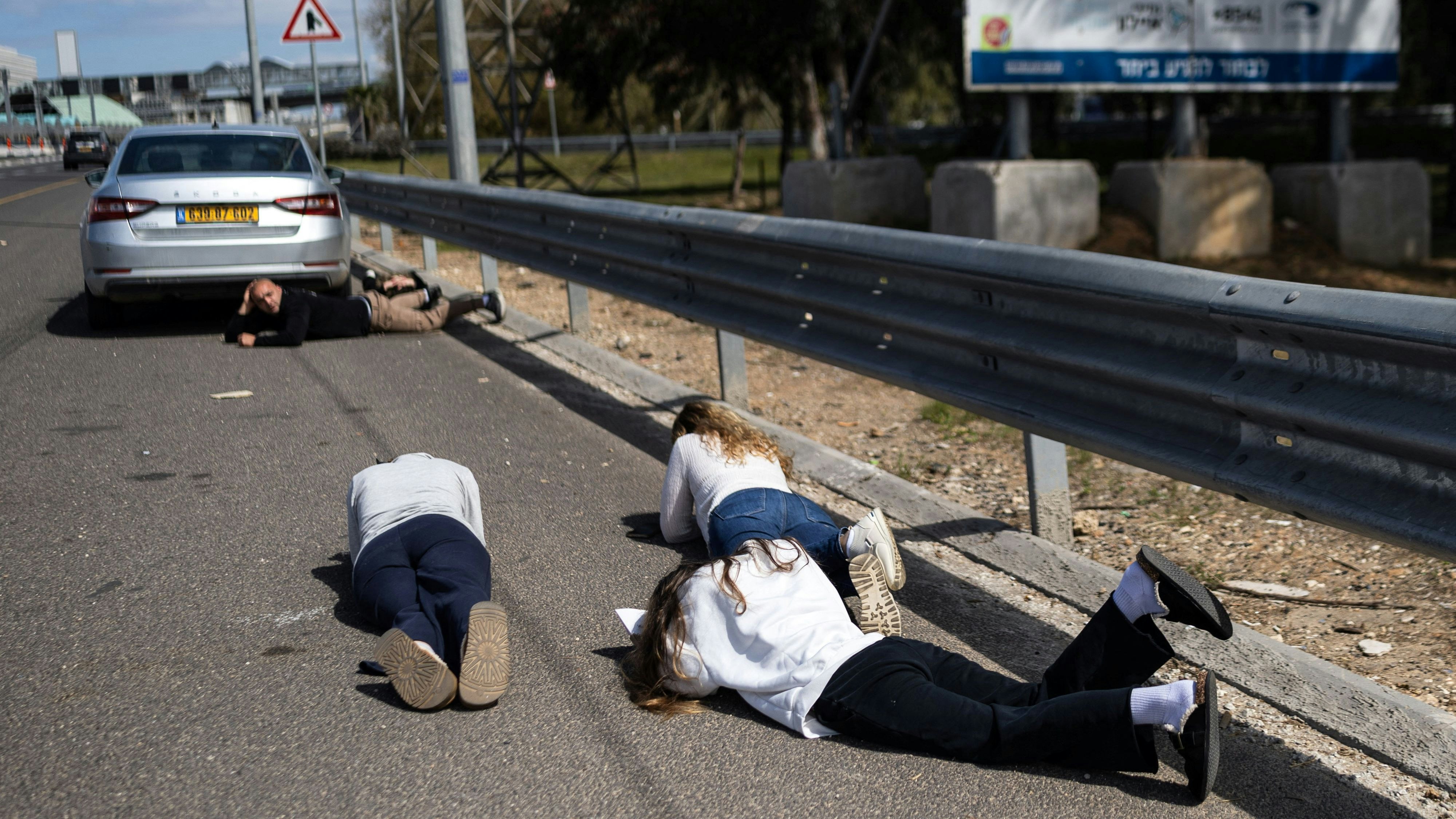 Israelis legen sich während einer Sirene nach einem Raketenangriff aus dem Iran auf die Straße, um Schutz zu suchen