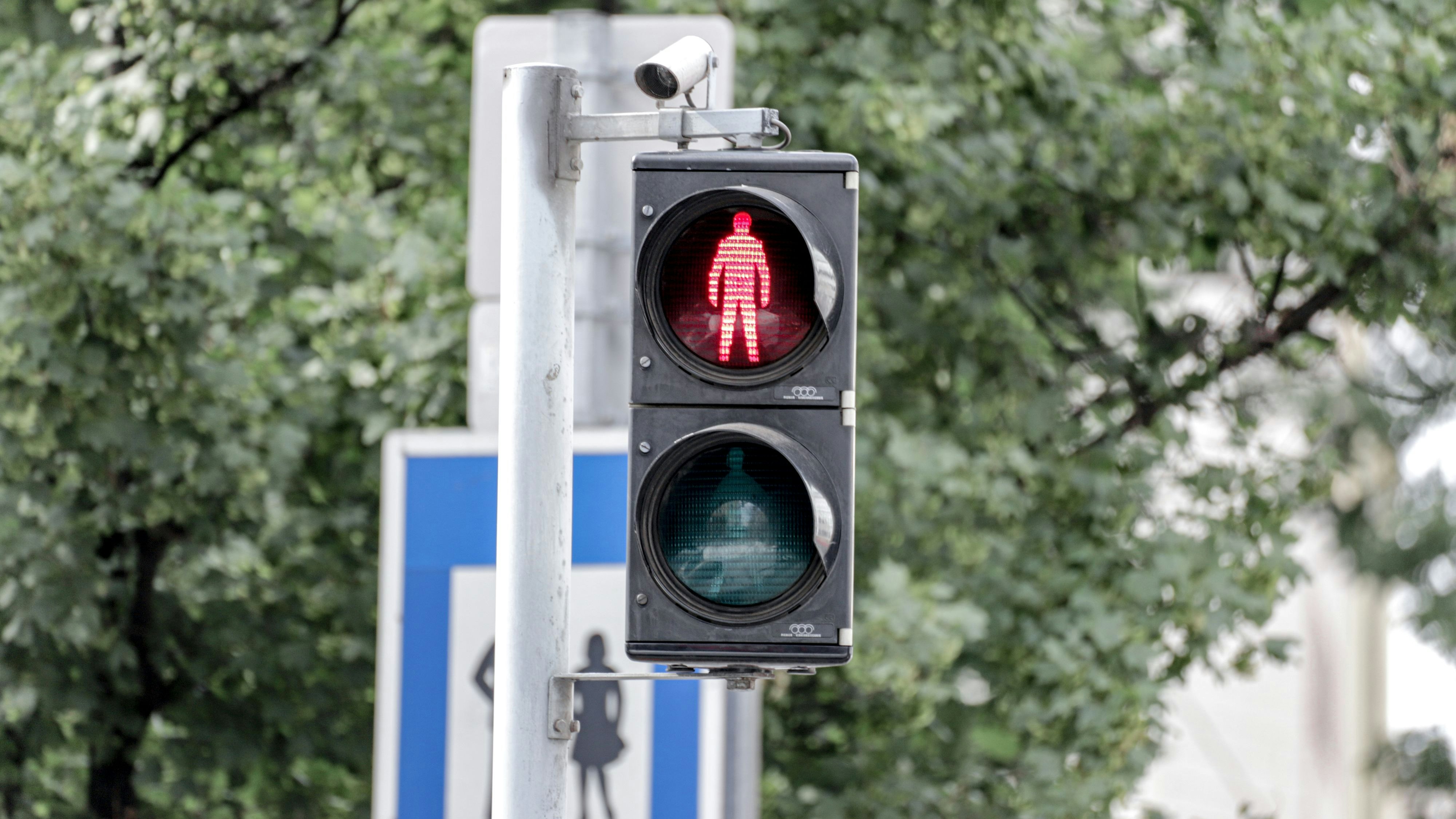 Auf einer Fußgängerampel ist eine Kamera montiert. Die Ampel steht auf rot. Wien, Österreich. Juni 2020
