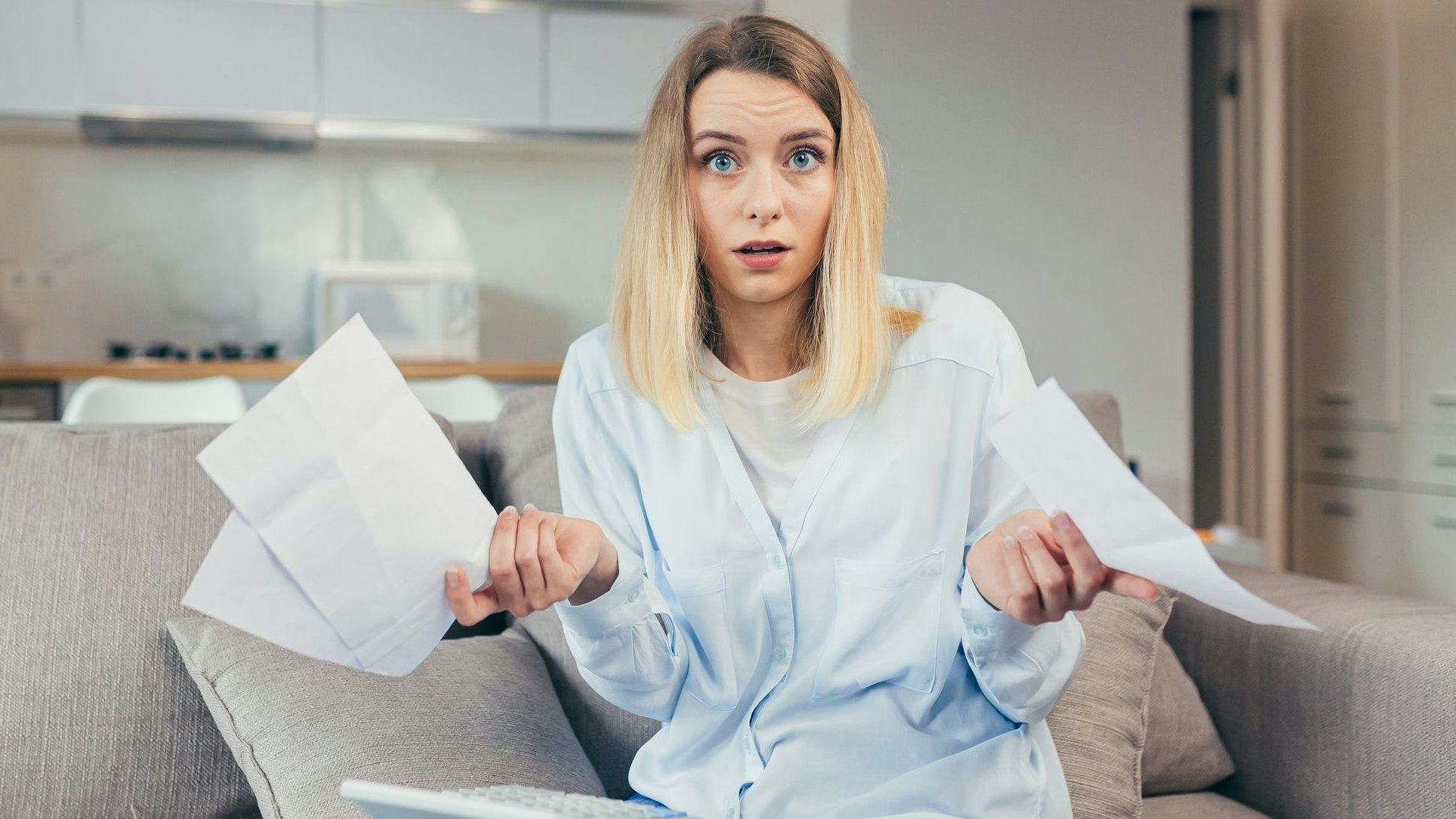 Worried housewife pays inflated bills while sitting on sofa at home, frustrated with work, and monthly income
