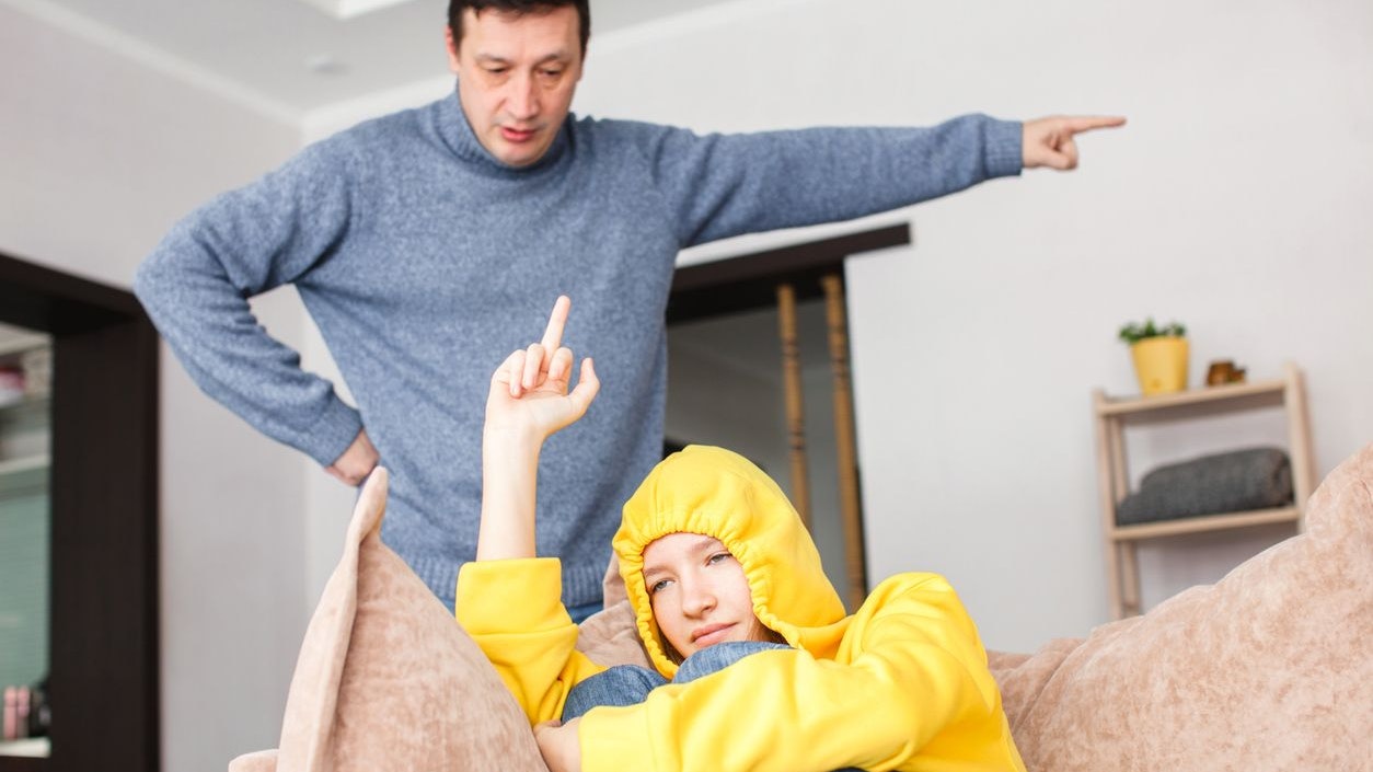 Dad swears at a naughty teenage girl. An unruly child shows fuck to his father. Family quarrel between parents and daughter at home