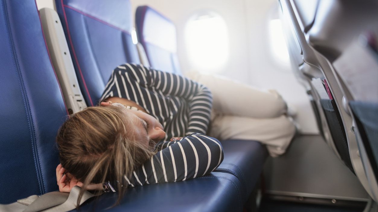 Young woman is travelling by plane. She is sleeping on three seats. Shot with Canon R5