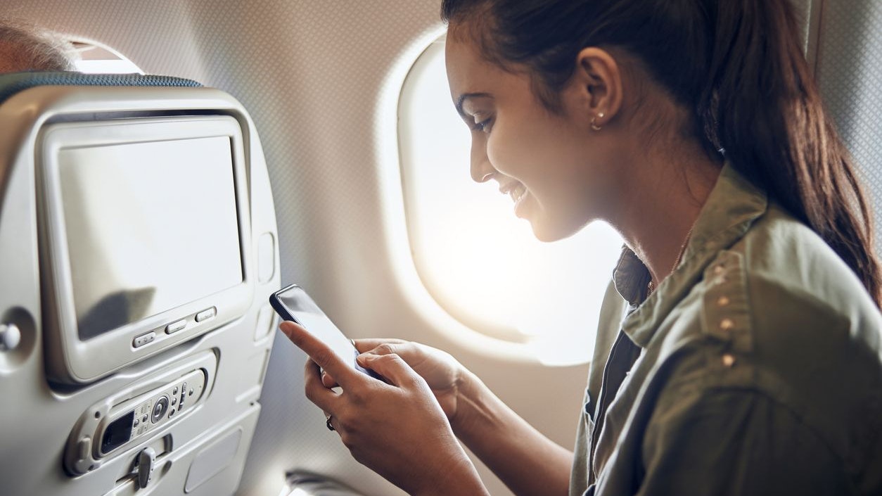 young businesswoman traveling for work and using her smartphone to pass time