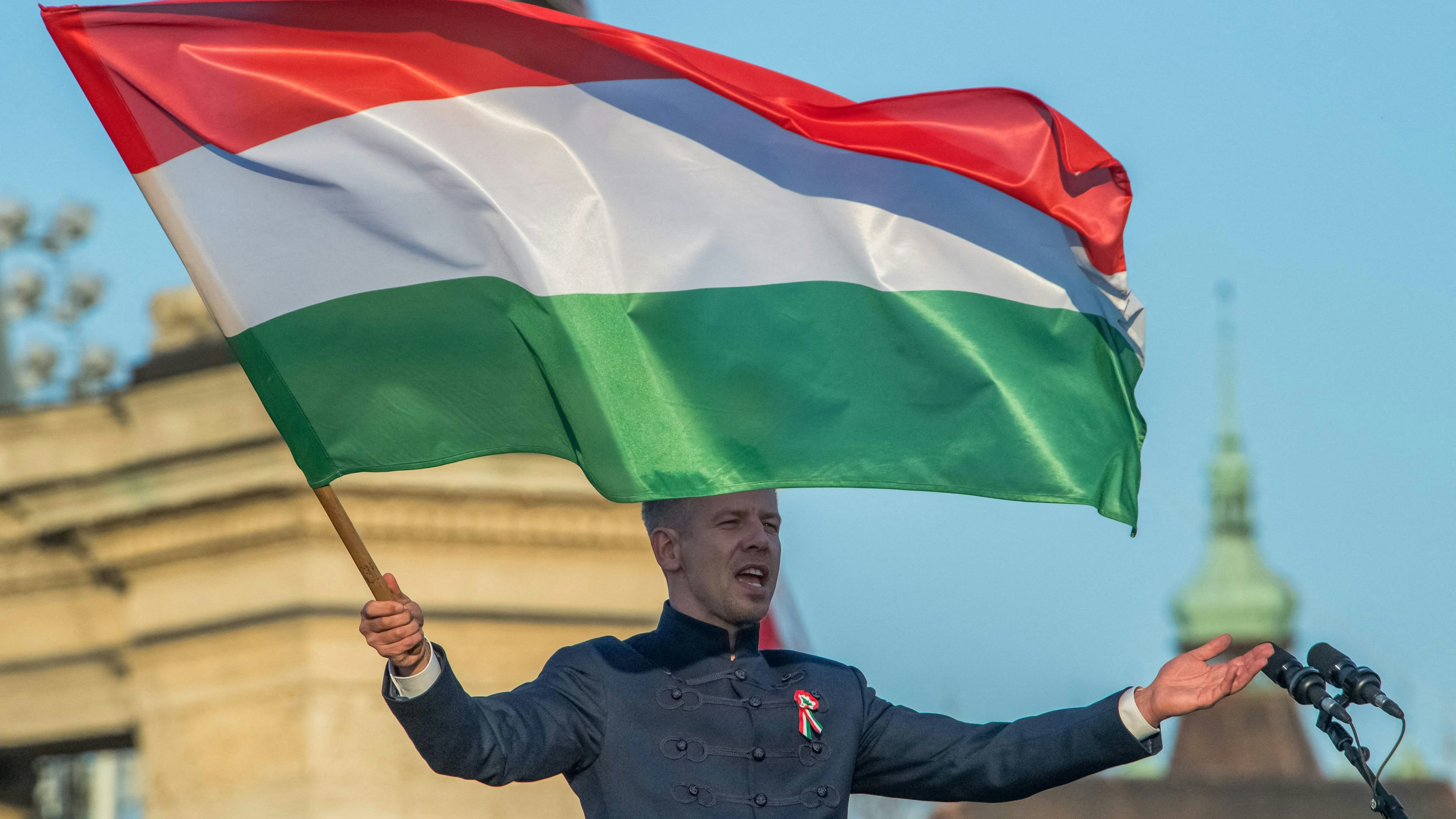 Hungarian opposition leader and president of the Tisza (Respect and Freedom) party Peter Magyar waves a Hungarian flag during a campaign rally organised by Hungary's Tisza party in Budapest, on Hungary's national holiday, March 15, 2026. The 1848-1849 revolution in the Kingdom of Hungary grew into a war for independence from the Austrian Empire, ruled by the Habsburg dynasty. (Photo by Ferenc ISZA / AFP)